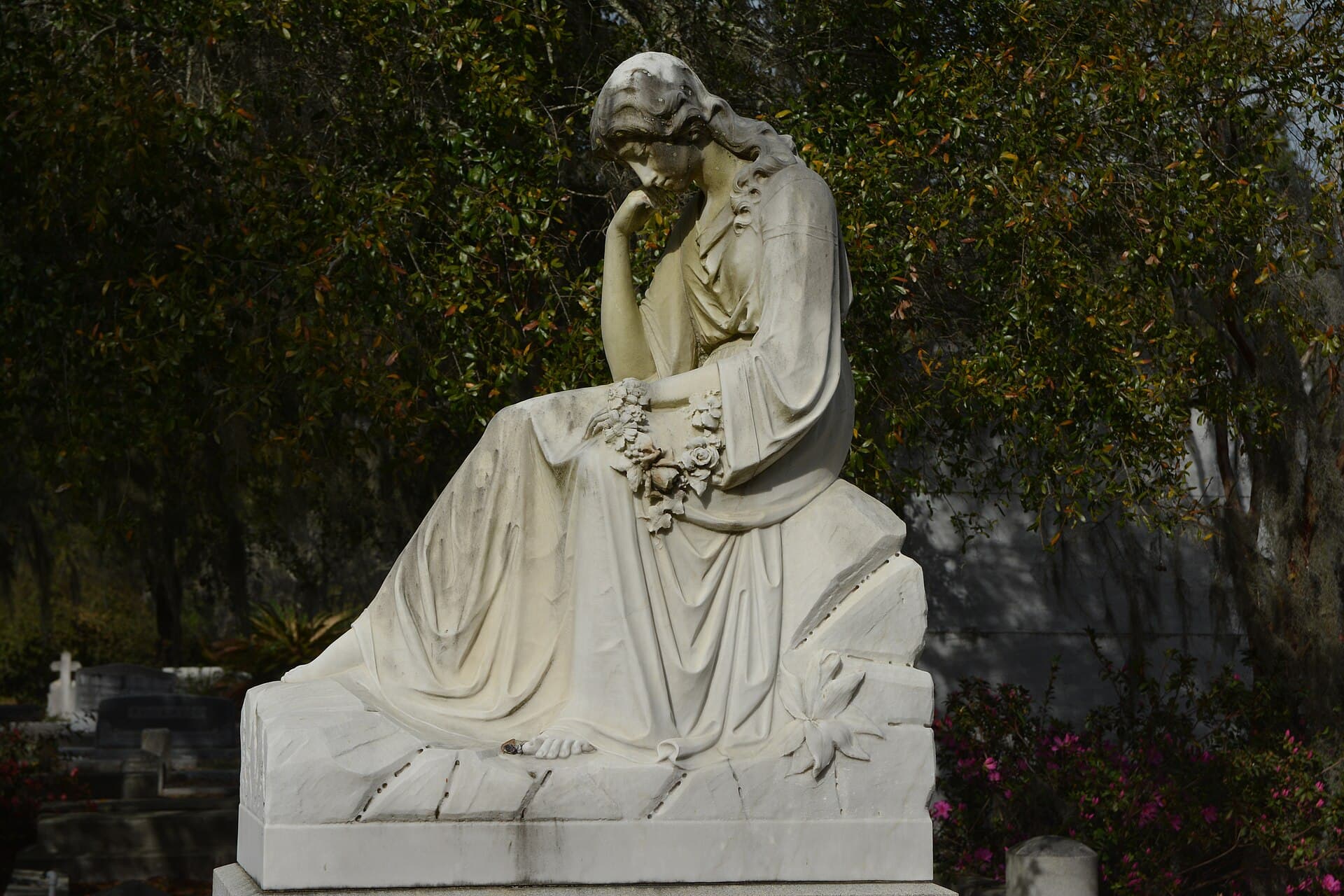 Marble statue of a seated woman among azaleas and live oaks at Bonaventure Cemetery, Savannah
